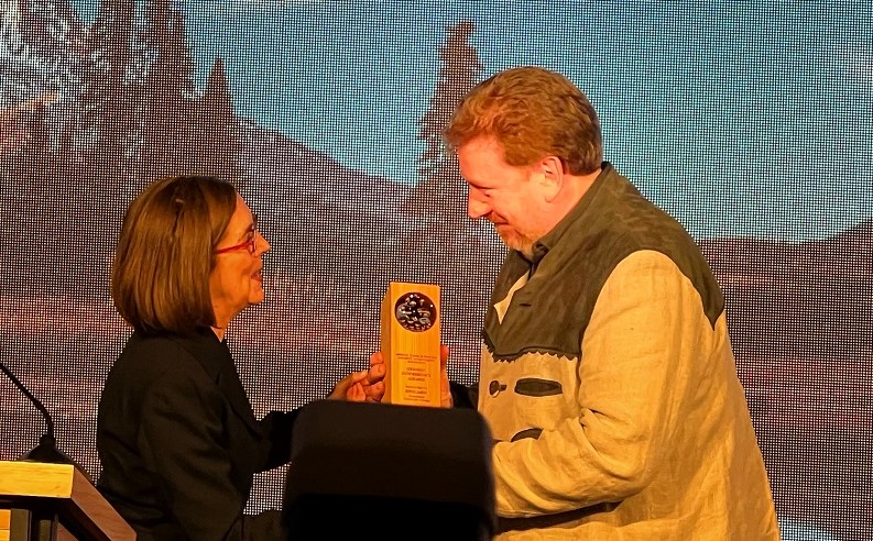 Eric Aebi receiving tourism award from Governor Kate Brown